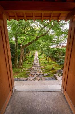 The view through the wooden gate to the garden with the stone road. Kyoto.Japan The view through the frame of old wooden-stock-foto