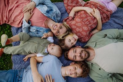 Top view of family lying on grass, portrait with two parents, son, daughter and small toddler outdoors in spring nature-stock-foto