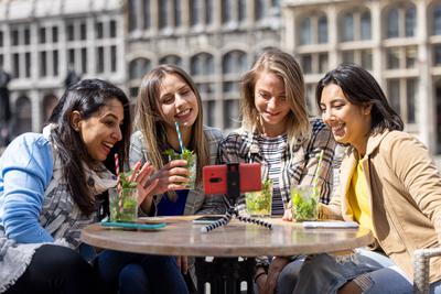 Antwerp, Belgium, May 21, 2021, Four multi ethnic female friends, tourists or students sitting at a cafe terrace in the-stock-photo