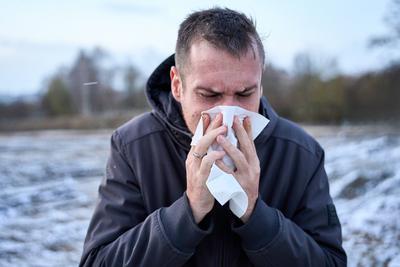 Bavaria, Germany - November 22, 2024: A man in a winter jacket blows his nose into a handkerchief outside. Symbolic imag-stock-foto