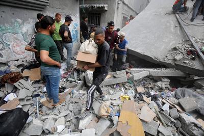 Palestinians inspect the rubble of a building following an Israeli strike on a residential area in Gaza City's Shujaiyya-stock-foto