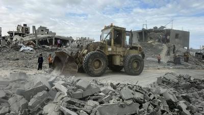 Palestinians inspect the site of an Israeli strike on tents and buildings site housing displaced people, in Khan Younis-stock-photo