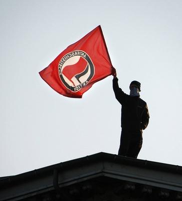 Aktivist der Antifa schwenkt die Fahne Demonstration zum 1 Mai in Berlin Kreuzberg-stock-photo