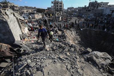 Palestinians gather around a large crater following an Israeli strike on a metalsmith workshop at the Zaytoun neighbouhood in Gaza City-stock-photo