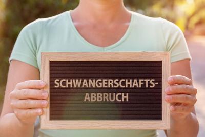 07 November 2022: Woman holding sign saying abortion. Termination of pregnancy by abortion PHOTOMONTAGE *** Frau h?lt Sc-stock-foto