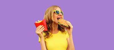 Portr?t einer gl?cklichen, fr?hlichen jungen Frau, die Burger und Pommes frites isst-stock-foto