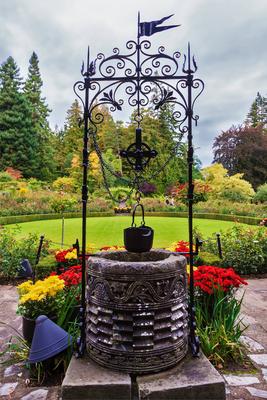 Decorative well Scenic decorative park Butchart Gardens on Vancouver Island, Canada. Decorative well on the green lawn C-stock-foto