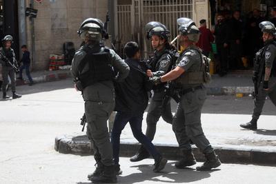 Israeli forces detain a Palestinian child during a raid as the army restrict the movement of citizens by closing shops-stock-foto
