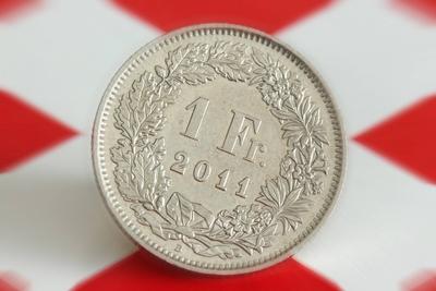 Symbolbild Kaufkraft des schweizer Franken Schweizer Franken M?nze liegt auf einer Flagge der Schwe-stock-photo
