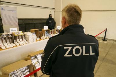 Beamter mit der Aufschrift Zoll auf seiner Jacke bewacht Viagra, Testosteron, Aufputschmittel Medikamente Verpackungen Gold und Geld liegen auf einem Tisch waehrend der Zoll Praesentation von sichergestellten Dopingmitteln, Drogen und Vermoegenswerten wie Bargeld und Gold in einer Halle auf dem Gelaende des Zollfahndungsamtes Hamburg17.04.2025 Der Hamburger Zoll hat einen illegalen Dopingmittel und Drogenvertrieb zerschlagen Die Beamten hatten einen Haendlerring von 3 Bruedern festgenommen die Sachen sichergestellt.Dabei wurden Verm?genswerte in H?he von 189.000 Euro in Bar sowie Gold im Wert von 50.000 Euro Hamburg Deutschland *** Officer with the inscription customs on his jacket guards Viagra, testosterone, stimulant drugs packaging go-stock-foto