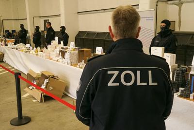 News Bilder des Tages Beamter mit der Aufschrift Zoll auf seiner Jacke bewacht Viagra, Testosteron, Aufputschmittel Medikamente Verpackungen Gold und Geld liegen auf einem Tisch waehrend der Zoll Praesentation von sichergestellten Dopingmitteln, Drogen und Vermoegenswerten wie Bargeld und Gold in einer Halle auf dem Gelaende des Zollfahndungsamtes Hamburg17.04.2025 Der Hamburger Zoll hat einen illegalen Dopingmittel und Drogenvertrieb zerschlagen Die Beamten hatten einen Haendlerring von 3 Bruedern festgenommen die Sachen sichergestellt.Dabei wurden Verm?genswerte in H?he von 189.000 Euro in Bar sowie Gold im Wert von 50.000 Euro Hamburg Deutschland *** Officer with the inscription customs on his jacket guards Viagra, testosterone, stimulant drugs packaging go-stock-foto