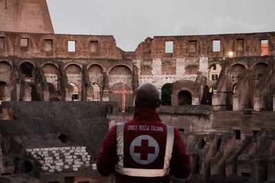 Rome, Via Crucis. Italian Red Cross volunteer observes the cross lit by flames inside the Colosseum..-stock-foto
