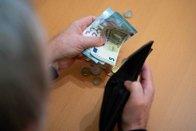 Munich, Bavaria, Germany - February 27, 2025: Several euro bills in one hand of an old man (pensioner with gray hair), w-stock-foto