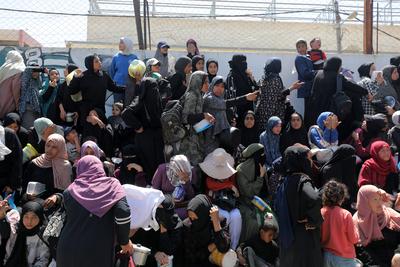 Palestinians, mostly children, wait in long lines with empty pots in hands to get a warm meal distributed by charitable-stock-foto