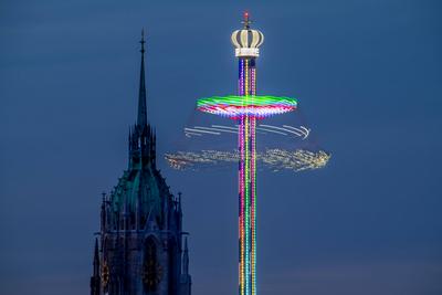 Der BayernTower leuchtet in den Abendhimmel, vor dem Kirchturm von St. Paul, M?nchner Fr?hlingsfest am Sonntagabend, M?nchen, 27. April 2025-stock-foto