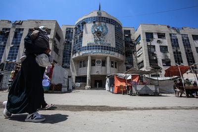 Displaced Palestinians sit by their makeshift tents outside the UNRWA-run clinic-stock-foto