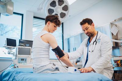 Teen boy undergoing medical checkup with doctor in hospital room.-stock-photo