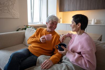 Gl?cklich verlobtes reifes Paar Frau Ehemann genie?t Gespr?ch beim Schl?rfen Tee zusammen auf gem?tlichen Sofa-stock-foto