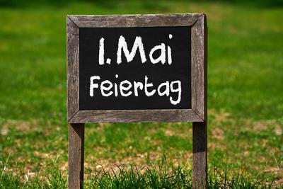 April 29, 2025: PHOTOMONTAGE, sign with the inscription May 1 holiday in a green meadow *** FOTOMONTAGE, Schild mit Aufs-stock-foto