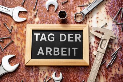 Bavaria, Germany - March 30, 2025: PHOTOMONTAGE, board with the inscription Labor Day between screws and tools. Symbolic-stock-foto