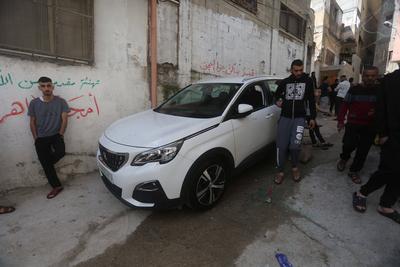 Palestinians stand near a destroyed car after an Israeli military raid on the Balata refugee camp, near the West Bank city of Nablus-stock-foto