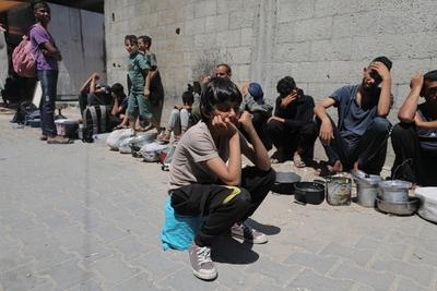 Palestinians wait in long queues to receive pots of food distributed by charitable organizations-stock-photo