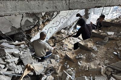 Palestinians inspect the damage caused by an Israeli airstrike targeting a school housing displaced people for the second time in Al-Bureij-stock-foto