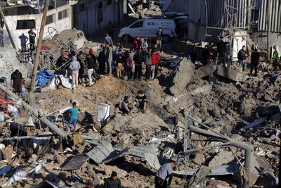 Palestinians inspect the damage caused by an Israeli airstrike targeting a school housing displaced people for the second time in Al-Bureij-stock-foto