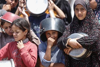 Palestinians wait in long queues to receive pots of food distributed by charitable organizations, in Gaza city-stock-foto