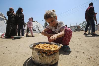 Palestinians wait in long queues to receive pots of food distributed by charitable organizations, in Gaza city-stock-foto