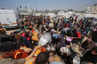 Palestinians wait in long queues to receive pots of food distributed by charitable organizations, in Gaza city-stock-foto