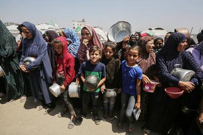 Palestinians wait in long queues to receive pots of food distributed by charitable organizations, in Gaza city-stock-foto