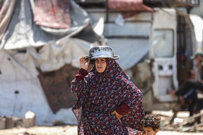 Palestinians wait in long queues to receive pots of food distributed by charitable organizations, in Gaza city-stock-foto