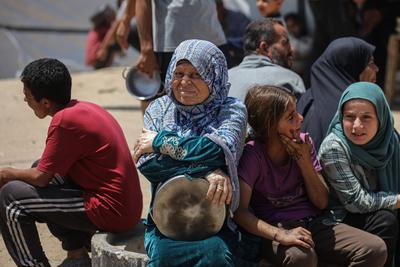 Palestinians wait in long queues to receive pots of food distributed by charitable organizations, in Gaza city-stock-foto