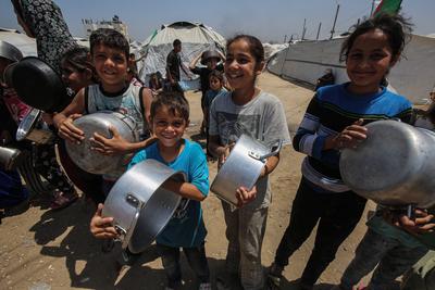 Palestinians wait in long queues to receive pots of food distributed by charitable organizations, in Gaza city-stock-foto