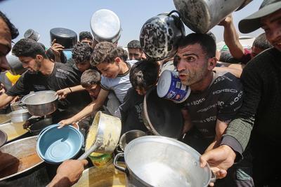 Palestinians wait in long queues to receive pots of food distributed by charitable organizations, in Gaza city-stock-foto