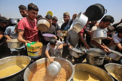 Palestinians wait in long queues to receive pots of food distributed by charitable organizations, in Gaza city-stock-foto