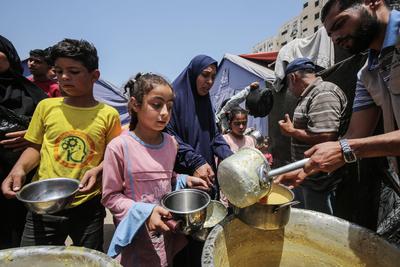 Palestinians wait in long queues to receive pots of food distributed by charitable organizations, in Gaza city-stock-foto