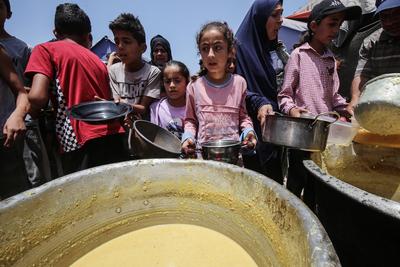 Palestinians wait in long queues to receive pots of food distributed by charitable organizations, in Gaza city-stock-foto