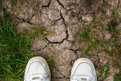 Bavaria, Germany - April 20, 2025: Symbolic image for climate change and drought. A person with white shoes stands in fr-stock-foto