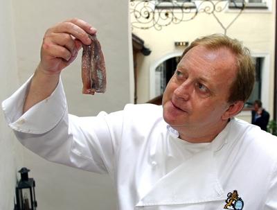 Koch Alfons Schuhbeck GER blickt skeptisch auf einen frischen Matjes Hering in Schuhbecks Kochsc-stock-foto