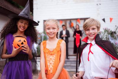 Kinder in Gespensterkost?men haben an Halloween viel Spa? beim S??es-oder-Saures-Spielen-stock-foto