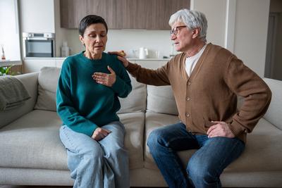 Gesundheitsprobleme eines ?lteren Paares. Ver?ngstigte Frau k?mpft mit Enge in der Brust und Schwindelgef?hl bei Herzinfarkt-stock-foto