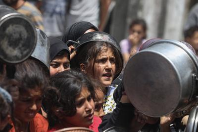 Palestinians wait in long queues to receive pots of food distributed by charitable organizations, in Jabalia-stock-foto
