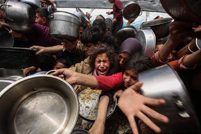 Palestinians wait in long queues to receive pots of food distributed by charitable organizations, in Jabalia-stock-foto
