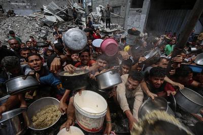 Palestinians wait in long queues to receive pots of food distributed by charitable organizations, in Jabalia-stock-foto