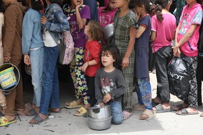 Palestinians who were able to receive the food distributed are eating as Palestinians, including children, who are struggling with hunger wait in line to receive hot meals distributed by the charity organizations-stock-foto