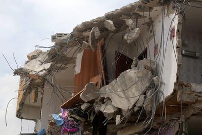 Palestinians inspect the damage around a destroyed building after Israeli troops besieged it and killed-stock-photo
