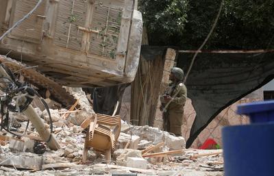 Palestinians inspect the damage around a destroyed building after Israeli troops besieged it and killed-stock-photo