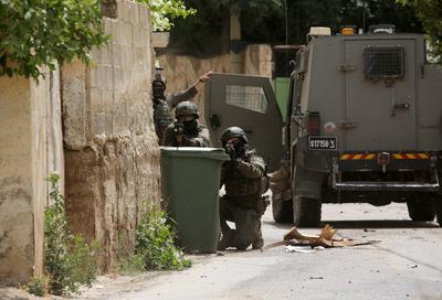 Israeli military vehicles and bulldozers surround a Palestinian house in the town of Tammun during an Israeli army raid in Tubas-stock-foto